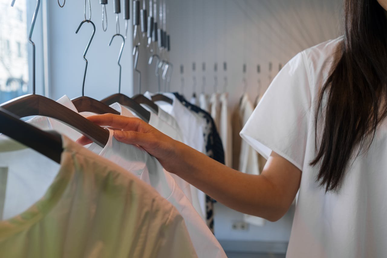 journey Close-up of a woman browsing clothes in a boutique, focusing on hangers.