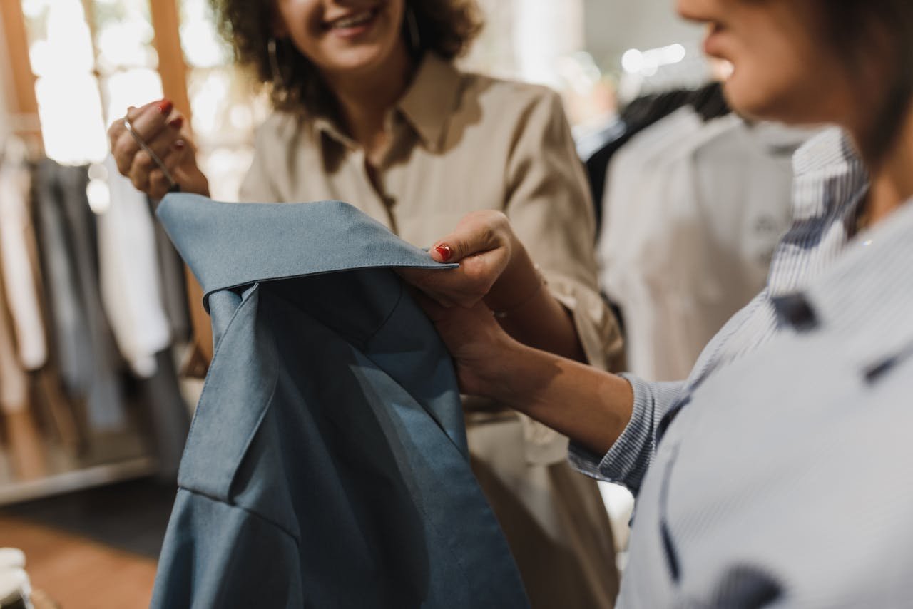 Women examining a blue garment in a modern boutique, highlighting a shopping experience.
