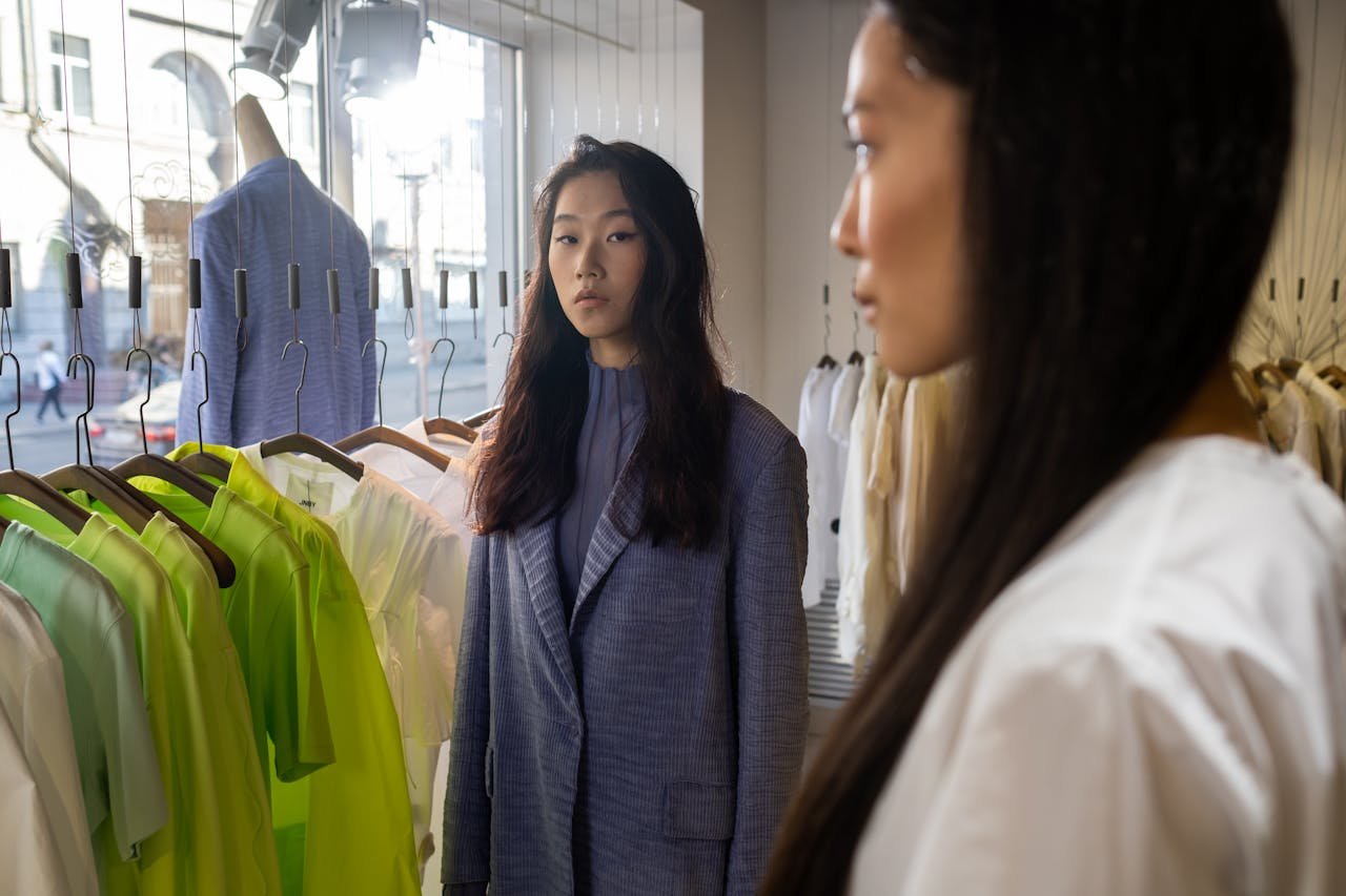 Two stylish women exploring a boutique clothing store with vibrant garments on display.